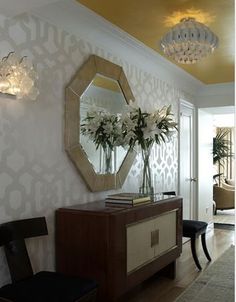 a living room filled with furniture and a chandelier above a mirror on the wall