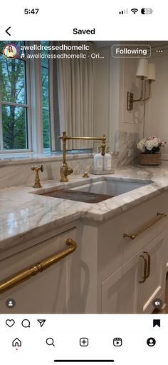 a kitchen with marble counter tops and gold faucets on the sink, in front of a window