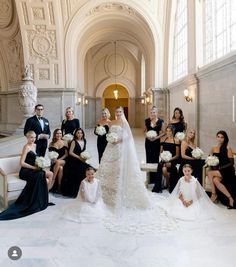 a bride and her bridal party pose for a photo in the grand hall at their wedding