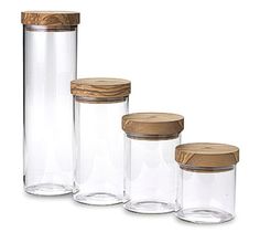 three glass jars with wooden lids are lined up