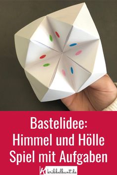 a hand holding an origami umbrella with the words basteln mit kindern himmel und holle mit augaben