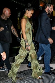 a woman in a green dress is walking down the street