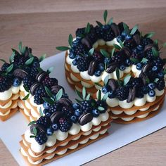 four desserts are arranged on a plate with berries and blueberries in the middle