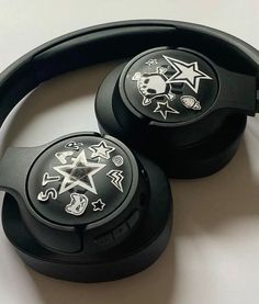 two black headphones sitting on top of a white table with skulls and stars painted on them