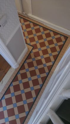 an overhead view of a tiled floor in a bathroom with a white door and brown and blue checkered tile