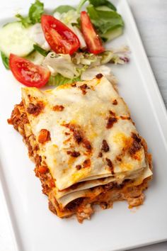 a white plate topped with lasagna and salad