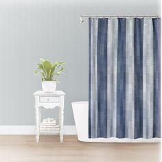 a blue and white striped shower curtain next to a small table with a potted plant on it