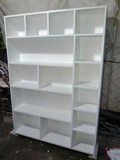 an empty white bookcase sitting on the ground