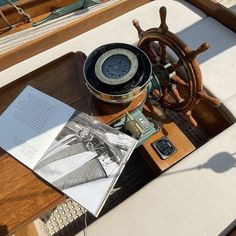 an open book sitting on top of a table next to a steering wheel and phone