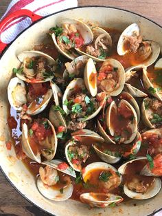 a pan filled with clams and sauce on top of a wooden table