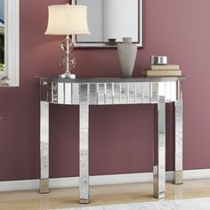 a silver console table with a lamp and mirror on the wall in front of it