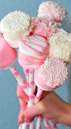 a person holding several pink and white candy lollipops