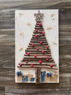 a christmas tree made out of sticks on top of a wooden board with red berries