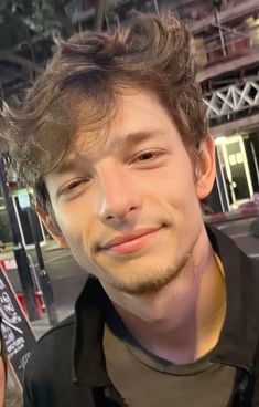 a close up of a person wearing a black shirt and smiling at the camera with his eyes closed