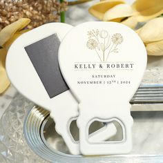 a couple of white bottle openers sitting on top of a metal tray next to flowers