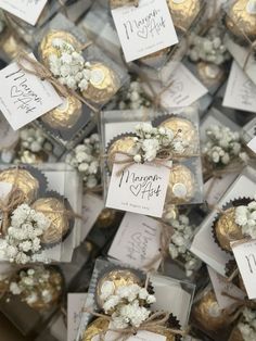 many small boxes filled with white flowers and gold foil wrapped in twine ribbons, tied together