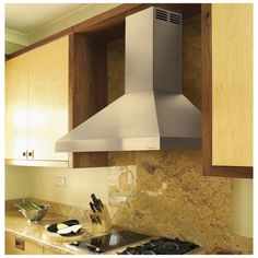 a stove top oven sitting inside of a kitchen next to wooden cupboards and counter tops