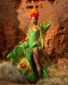 a woman in a green dress with orange flowers on her head and hands, posing for the camera