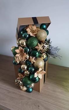 a box with ornaments in it sitting on top of a wooden table next to a plant