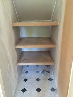 an empty shelf in the corner of a room with tile flooring and white walls