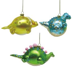 three ornaments in the shape of dinosaurs hanging from strings