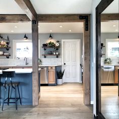 an open concept kitchen and dining room with wood flooring, white walls and wooden beams