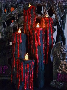 three candles with red and black icing on them sitting in front of halloween decorations