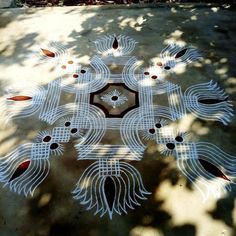 an intricately designed design on the ground in front of a tree with lots of leaves