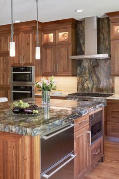 a large kitchen with wooden cabinets and marble counter tops, stainless steel appliances and an island in the middle