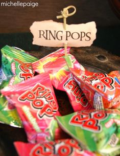 a pile of candy sitting on top of a wooden table next to a sign that says ring pops