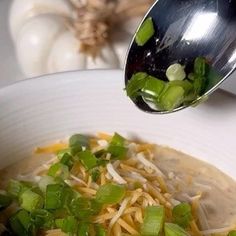 a white bowl filled with soup and topped with green onions