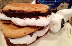 three cookies and marshmallows stacked on top of each other with chocolate sauce