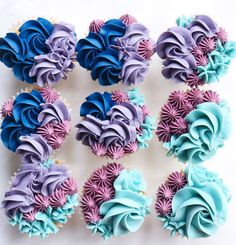 cupcakes with blue, purple and pink frosting are arranged on a white surface