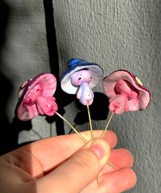 three small pink and blue flowers are held in someone's hand