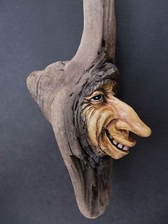 a wooden mask hanging on the wall with an open mouth and large, crooked teeth