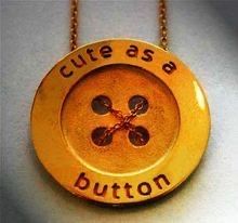 a gold necklace with the words cute as a button written in black ink on it