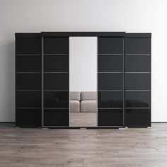 a black and white closet with mirrored doors in an empty room next to a couch