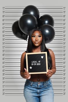 a woman holding a sign with balloons on her head