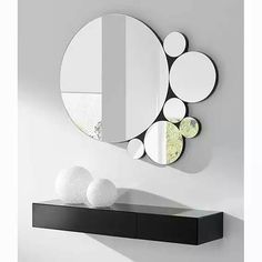 there is a black shelf with mirrors on it and two white balls in front of the mirror