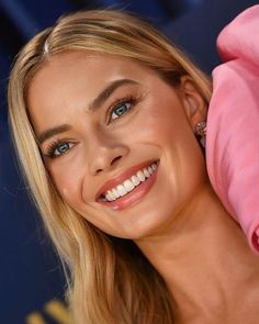 a close up of a woman with blue eyes and blonde hair smiling at the camera