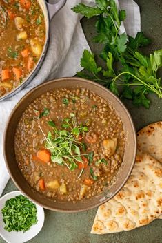 a bowl of lentula soup next to some pita bread