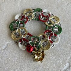 a multicolored christmas wreath with bells on the front and back of it, sitting on a white surface