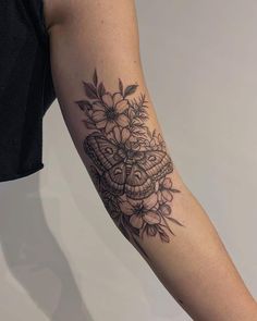 a woman's arm with flowers and a butterfly tattoo on the left upper arm