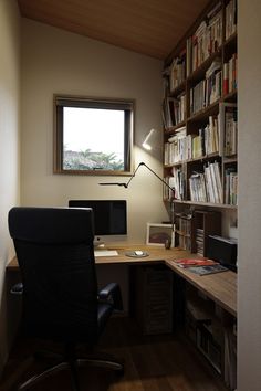 a home office with a desk, bookshelf and chair in front of the window