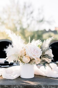 a white flower arrangement sitting on top of a wooden table