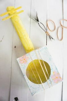 an image of crafting with yarn and scissors on white wood background that says easy upcycled guitar let's make music