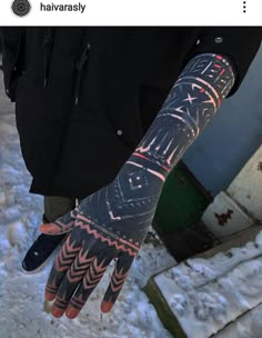 a person with a tattoo on their arm and hand in the middle of snow covered ground