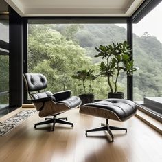 an eames chair and ottoman in front of a large window with trees outside it