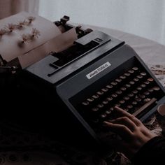 a person typing on an old fashioned typewriter with a cup of coffee next to it