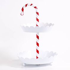 a paper candy cane is in a white bowl on a stand with red and white stripes